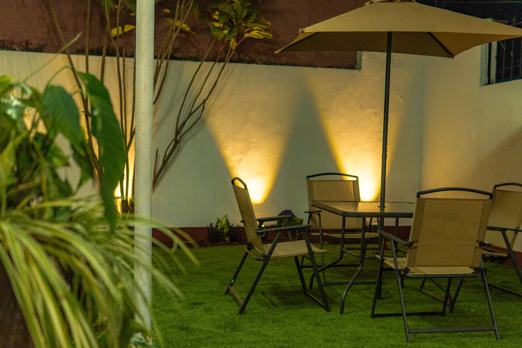 Patio de Los Olivos por la noche con jardín y área de mesas